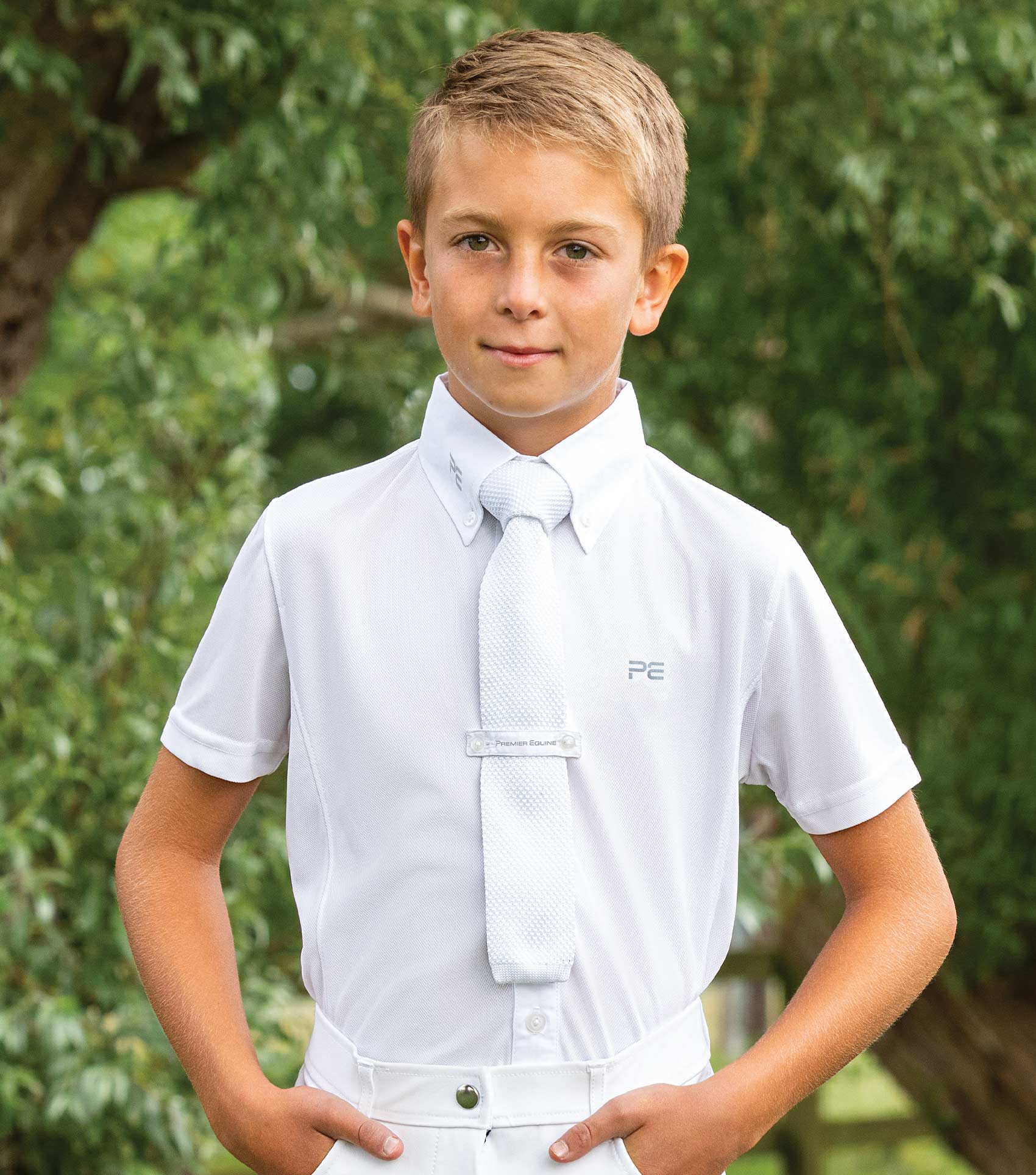Boy in white PREMIER EQUINE short sleeve show shirt with tie, equestrian competition attire.