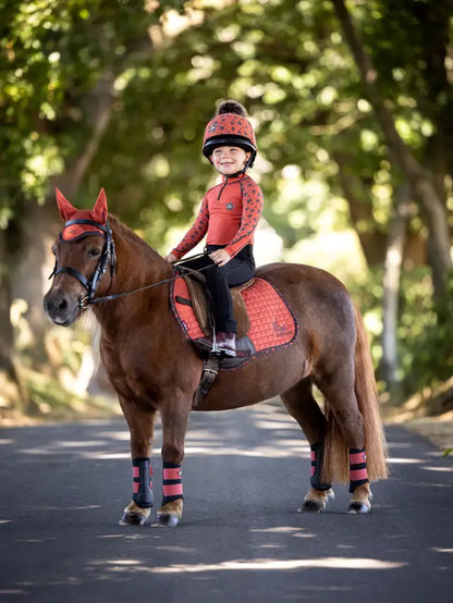 Child on pony wearing matching LEMIEUX Sienna base layer, helmet, and horse riding accessories from Equiflair.