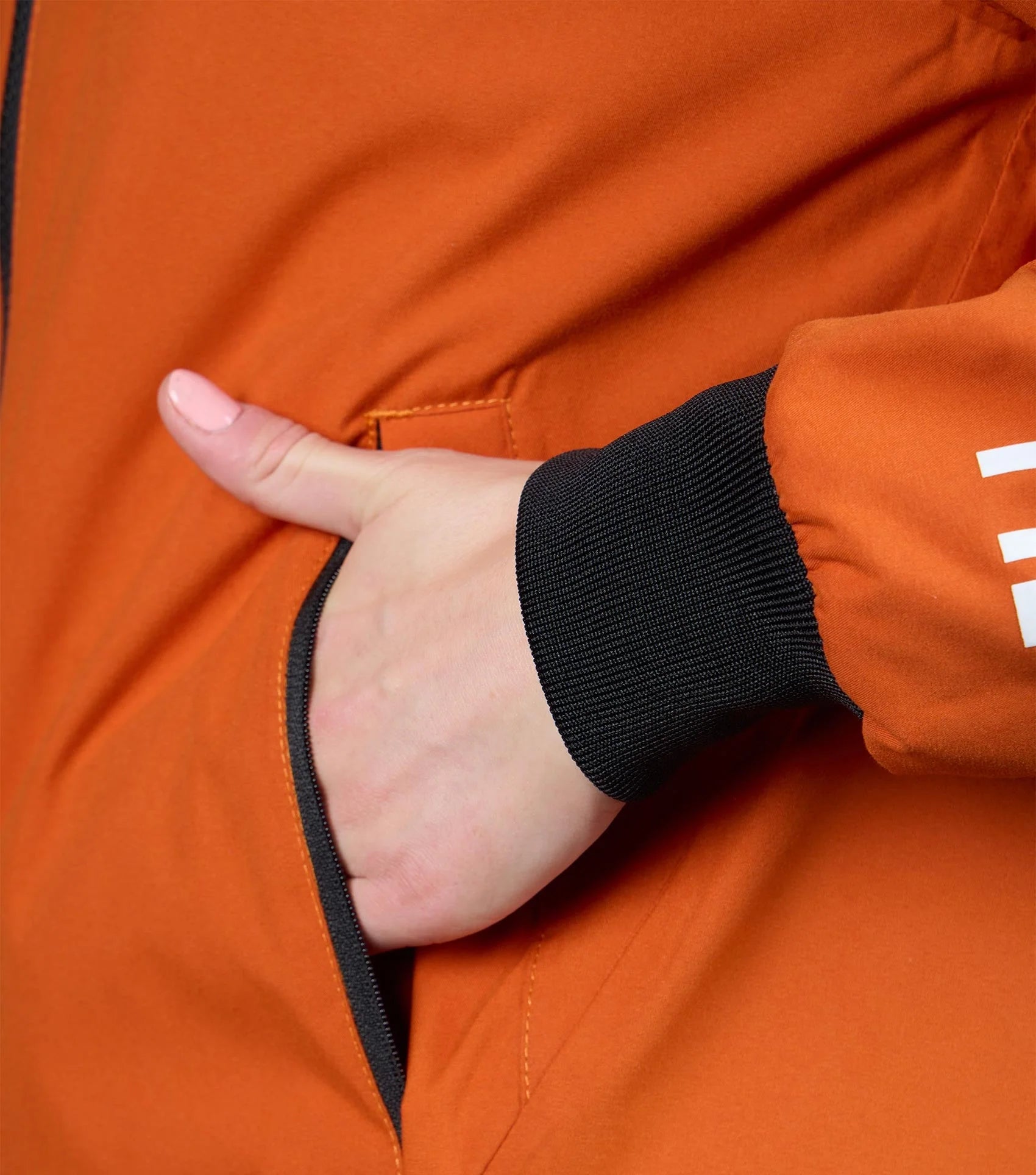 Premier Equine Waterproof Riding Jacket in Burnt Orange: Hand in pocket detail.