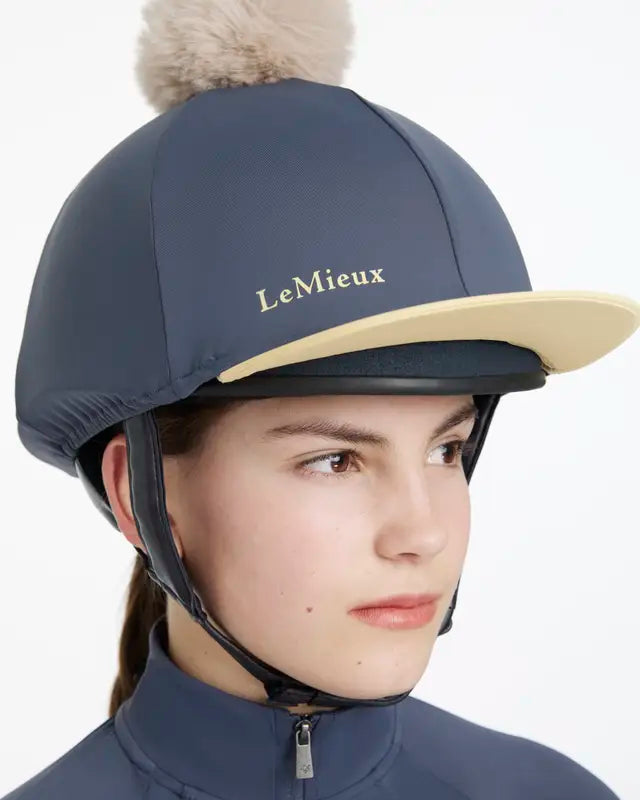 LEMIEUX POM HAT SILK DUSK/MIMOSA: Equestrian helmet cover with detachable faux fur pom pom, contrast peak, snug fit.