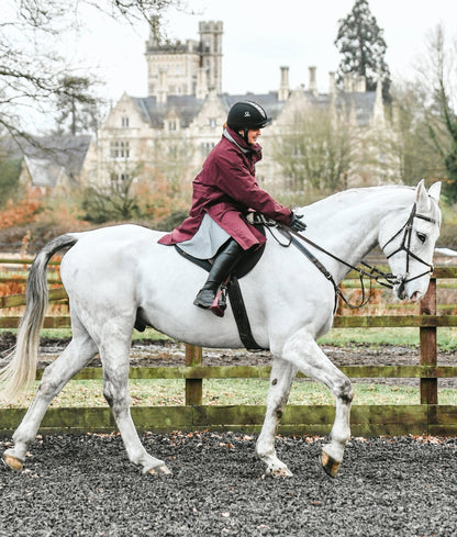 Equestrian in Burgundy Equiflair Reincoat riding Grey Horse near Castle. Horse Riding, Dressage. Reflective Reincoat.