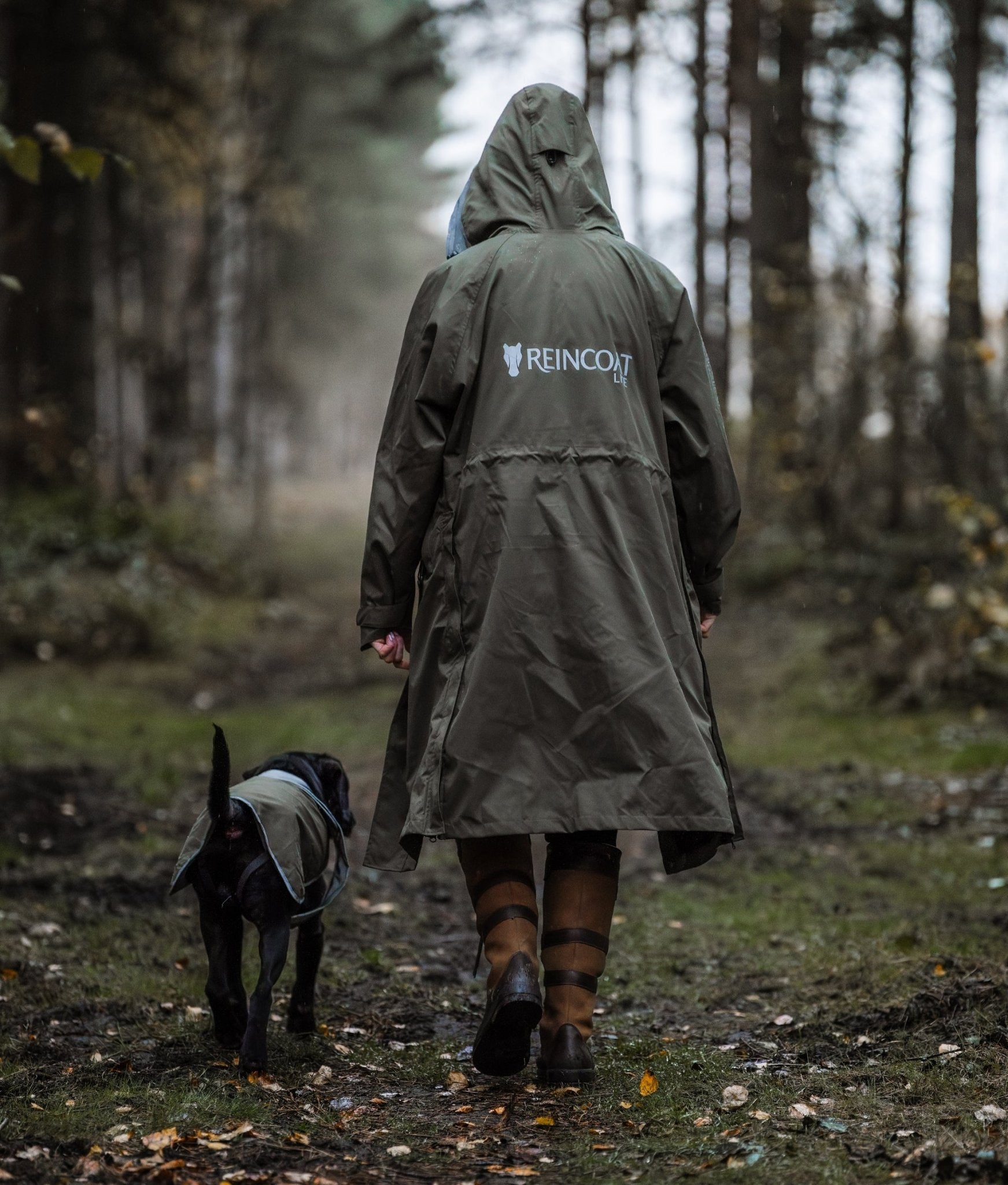 Dog Walking in Forest with REINCOAT Olive Raincoat. Waterproof Outdoor Clothing for Women.