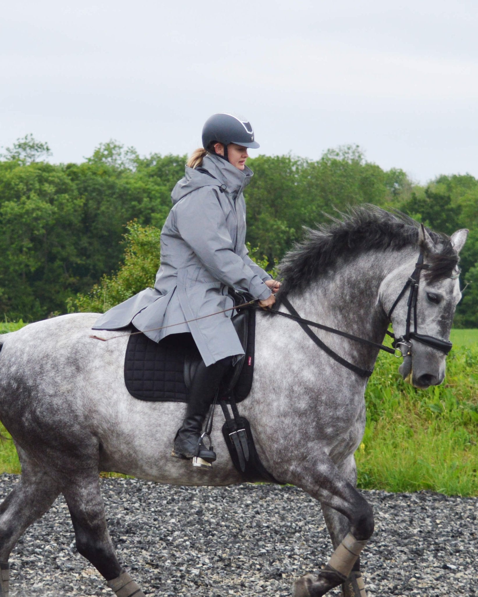 Woman riding a horse wearing an Equiflair reflective waterproof horse riding coat.