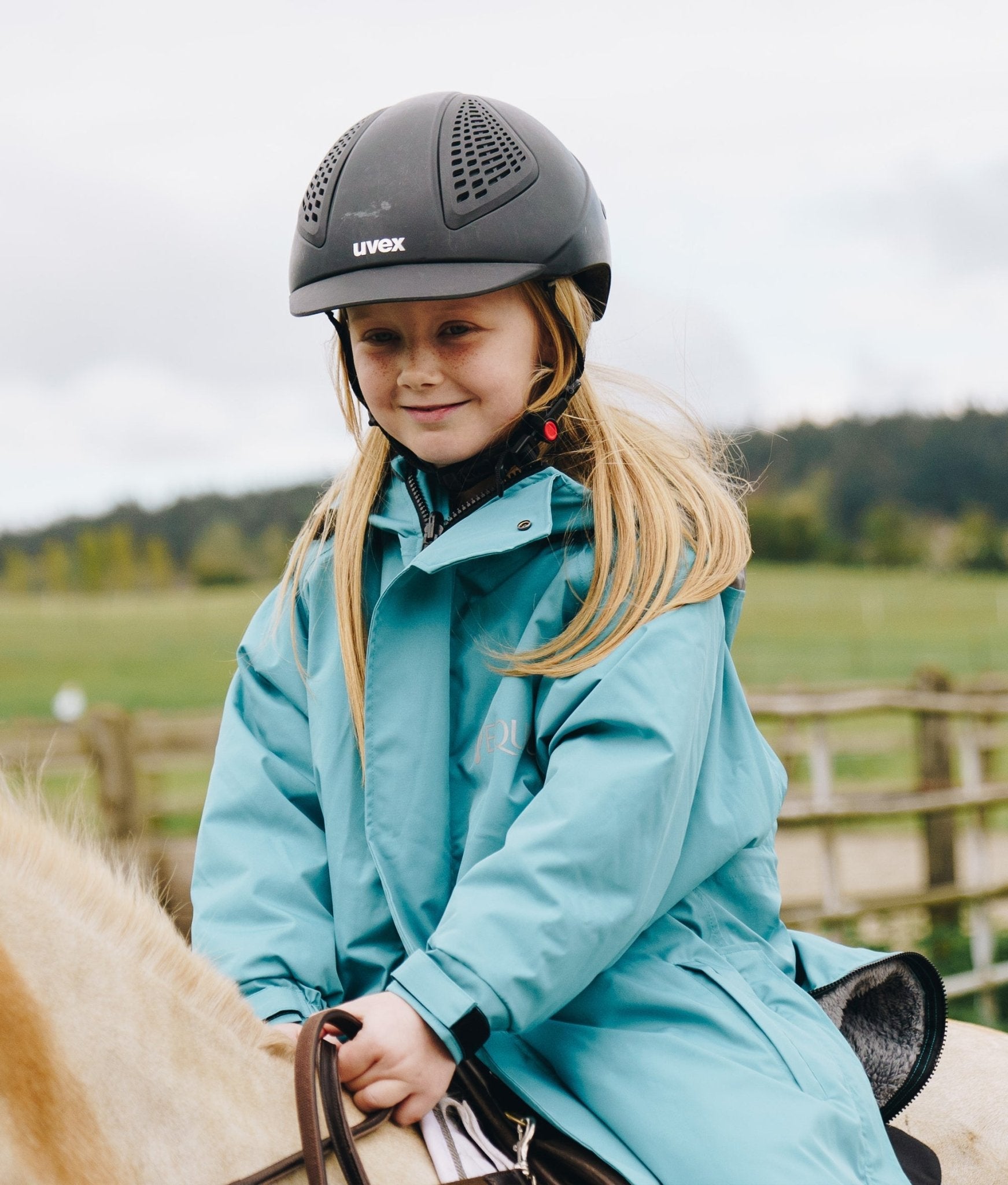 Girl Riding Horse in Teal Reincoat Pro Kids Jacket by Equiflair: Waterproof Equestrian Apparel for Young Riders, Warm Riding Gear