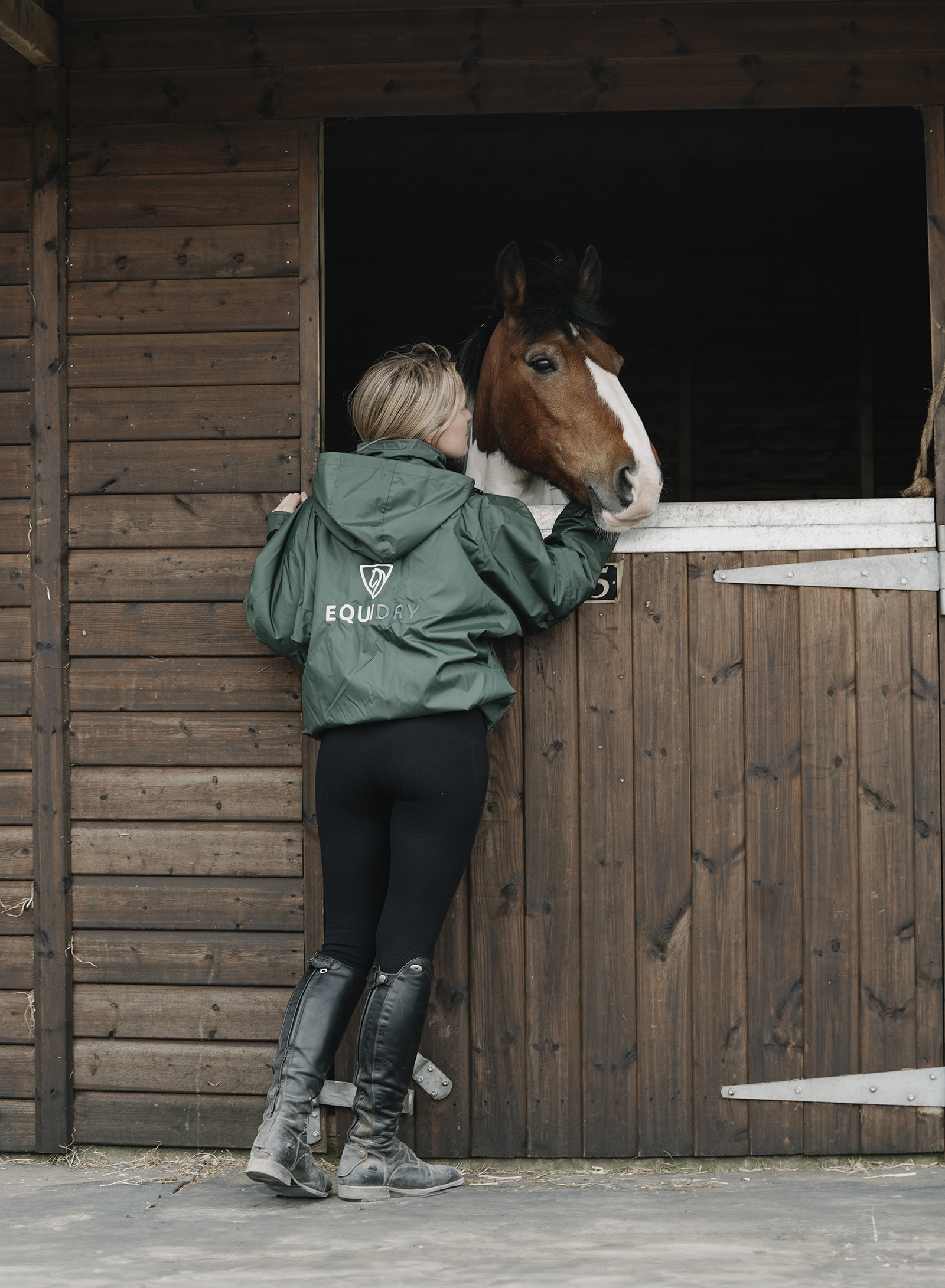 EQUIDRY women's waterproof short blouson style horse riding jacket in black forest green lifestyle with horse