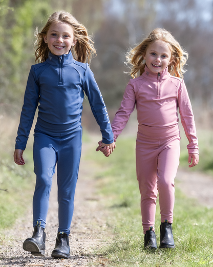Two girls in equestrian water repellent base layers - steel blue and pink - holding hands on a path