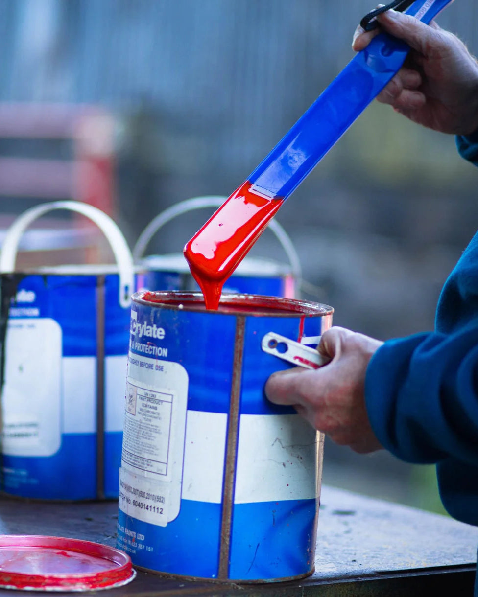 Red Gorilla Stir Up tool mixing red paint in blue can. Stirring Paint. Durable paint stirrer. DIY project.