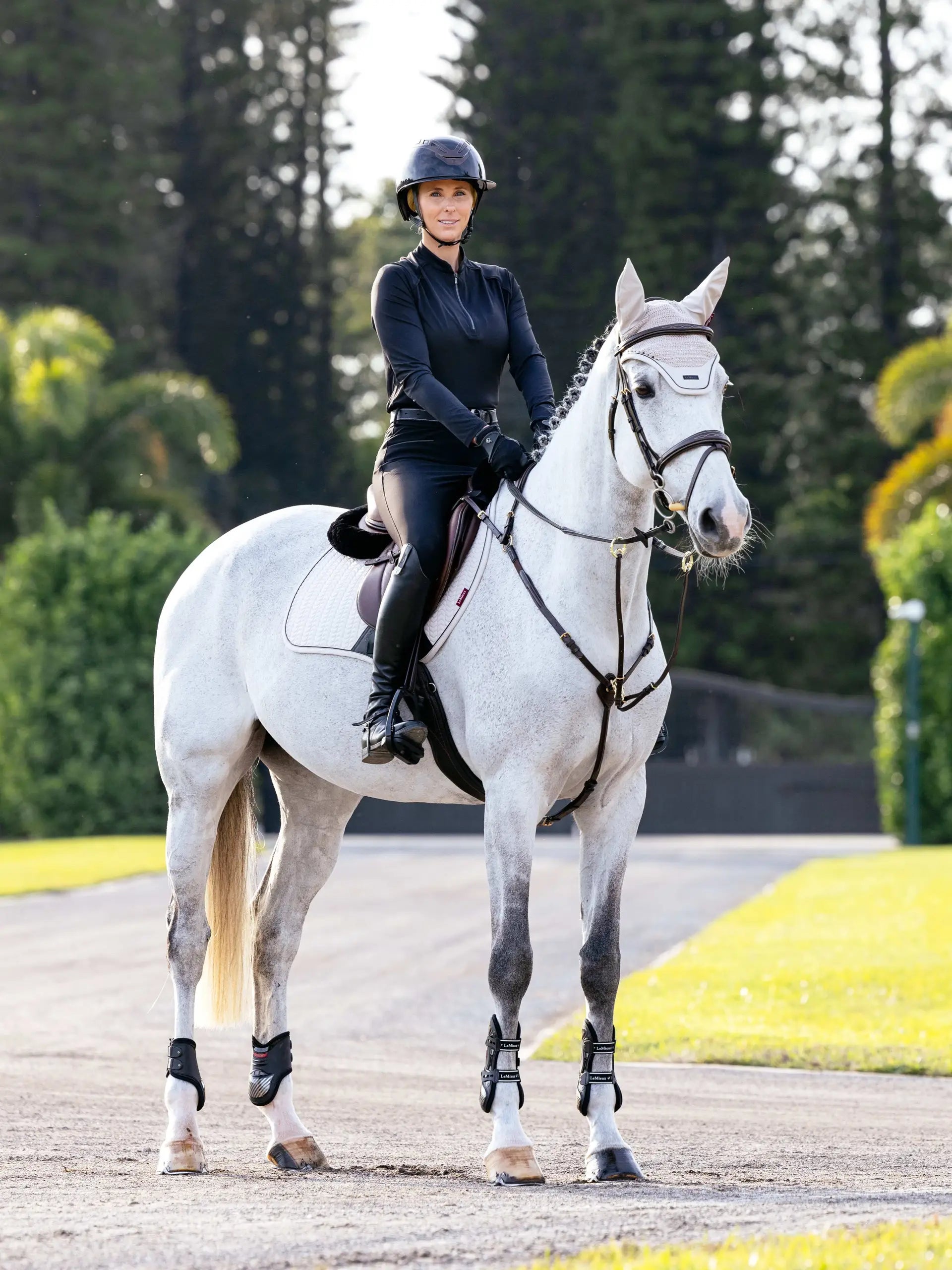 Equestrian elegance: Woman riding a grey horse wearing LeMieux gear. Shop now!